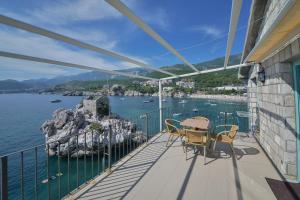 a balcony with a table and chairs and the water at Kazanegra Exclusive Apartments in Sveti Stefan