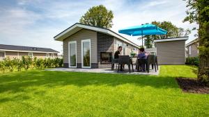 two people sitting at a table under an umbrella in a yard at TopParken – Résidence de Leuvert in Cromvoirt