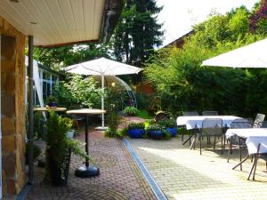 eine Terrasse mit Tischen, Stühlen und Sonnenschirmen in der Unterkunft Landhaus-Püttmann in Fröndenberg