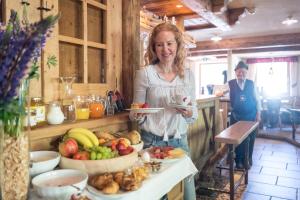 a woman standing in a kitchen holding a plate of fruit at Bar Garni Reischnhitt des Eschgfeller Christoph in Sarntal