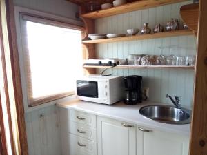 a kitchen with a sink and a microwave on a counter at Revontuli Resort Cottages in Hankasalmi