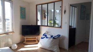 a living room with a television and a pillow at Appartement dernier étage Hyper Centre in Granville