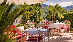 eine Terrasse mit Tischen, Stühlen und einem Sonnenschirm in der Unterkunft Hotel Behringer's Traube in Badenweiler