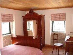 1 dormitorio con 1 cama, 1 silla y 2 ventanas en MyStay - Casa da Porta, en Baião