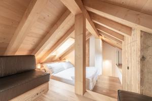 ein Schlafzimmer im Dachgeschoss mit einem Bett und einem Sofa in der Unterkunft Alla Stazion Locanda nelle Dolomiti in Pieve di Cadore