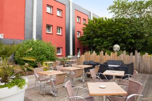 un patio con tavoli, sedie e recinzione di Kyriad Direct Rennes Ouest a Vezin-le-Coquet