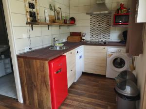 Il comprend une cuisine équipée d'un réfrigérateur rouge et d'un lave-linge. dans l'établissement Gite L'Ane Qui Rit, à Le Breuil