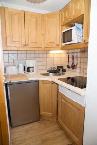 a kitchen with wooden cabinets and a sink and a microwave at Marmottin1 in Puy-Saint-Vincent