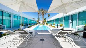 英格兰海滩Hotel Nayra - Adults Only的建筑物旁边有带椅子和遮阳伞的游泳池
