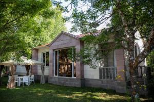 une maison rose avec une table et un parasol dans l'établissement Garden Inn Resort Sevan, à Sevan