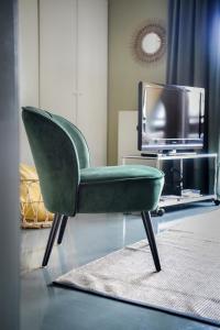 - Silla verde en la sala de estar con TV en Messeapartment Sunny Side, en Düsseldorf