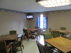 a dining room with tables and chairs and a television at Americourt Hotel and Suites - Elizabethton in Elizabethton