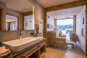 a bathroom with a sink and a large mirror at Hotel Zentral ****superior in Kirchberg in Tirol