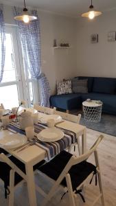 a dining room table with chairs and a blue couch at Apartament Baltic Relax in Rowy
