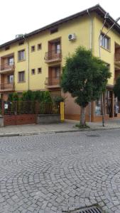 a building with a tree in front of a brick road at Къща за гости Фантазия in Tryavna