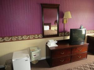 a room with a television on a dresser with a mirror at Americourt Hotel and Suites - Elizabethton in Elizabethton