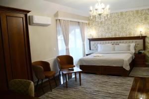 a bedroom with a bed and two chairs and a chandelier at Hotel Begolli in Prishtinë