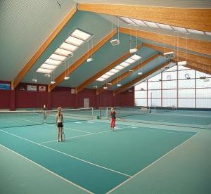 un grupo de personas jugando al tenis en una pista de tenis en Hotel Trebeltal, en Demmin