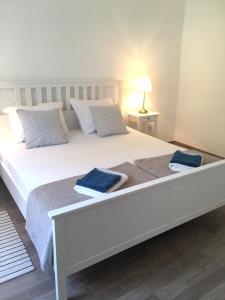 1 cama blanca grande con 2 toallas azules. en Stone & Salt Getaway Home, en Šimuni
