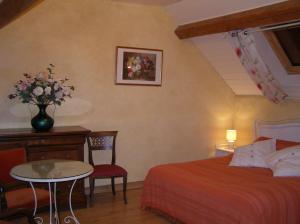 a bedroom with a bed and a table with a vase of flowers at Grange de la Herde in Camon