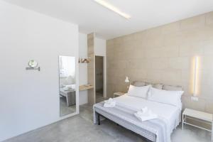 a white bedroom with a bed and a bench at NC Boutique B&B in Torre San Giovanni Ugento