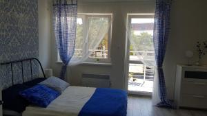a bedroom with a bed with blue curtains and a window at Apartament Baltic Relax in Rowy