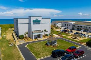 an aerial view of a building with cars parked in a parking lot at John Yancey Oceanfront Inn in Kill Devil Hills