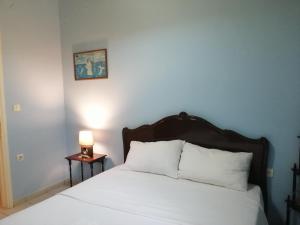 Una cama con sábanas blancas y una lámpara sobre una mesa. en Rodomelo House - 3 Bedrooms, en Leonidio