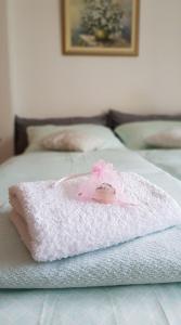 Una toalla blanca con una flor rosa en la cama en APARTMA SVETINA, en Bled