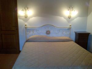 1 dormitorio con 1 cama blanca y 2 luces en la pared en Agriturismo Bonacchi, en Montalcino