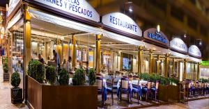 un restaurante con sillas azules frente a un edificio en Beach Front Penthouse - Fuengirola, en Fuengirola