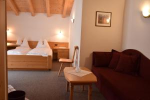 a hotel room with a bed and a couch at Garni Haus Tyrol in Corvara in Badia