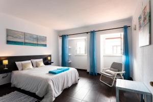 1 dormitorio con 1 cama con cortinas azules y silla en Casa da Mó - Santo Isidoro, en Santo Isidoro