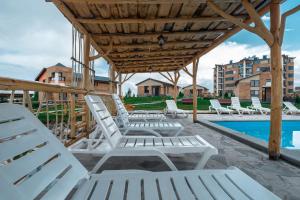 un gruppo di sedie a sdraio bianche su un patio con piscina di Tsovasar Family Rest Complex a Sevan