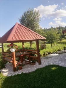 cenador de madera con mesa de picnic en el césped en Guest House Mila, en Plitvički Ljeskovac