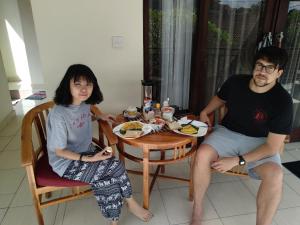 Um homem e uma mulher sentados à mesa com comida. em Nengah House Ubud em Ubud