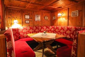 un restaurante con sofá rojo y mesa en Hotel Garni Kirchenwirt en Sankt Leonhard im Pitztal