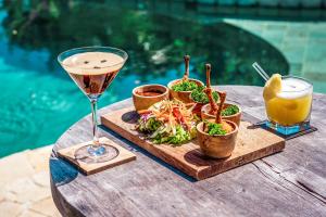 a drink and a plate of food on a wooden table at Green Escape Eco Resort in Uluwatu