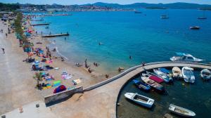 grupa ludzi na plaży z łodziami w wodzie w obiekcie Apartments Bosana XIV w Biogradzie na Moru