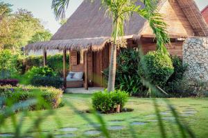 a cabin with a thatched roof in a garden at Green Escape Eco Resort in Uluwatu