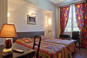 - une chambre avec un lit et une table avec une lampe dans l'établissement Hôtel et Résidence des Bains, à Vic-sur-Cère