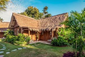een huis met een rieten dak en een tuin bij Green Escape Eco Resort in Uluwatu