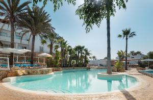 a large swimming pool with palm trees in a resort at Hotel Palia Puerto del Sol in Cala d´Or