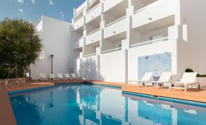 una piscina con sillas y un edificio en Hotel Palia Puerto del Sol en Cala d´Or