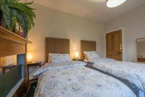 two twin beds in a bedroom with two lamps at The West End Cottage in Edinburgh