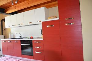 cocina roja con armarios blancos y fogones en Holiday house with garden and enchanting view en Villeneuve
