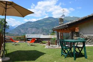 un patio con sillas, una mesa y una sombrilla en Holiday house with garden and enchanting view en Villeneuve