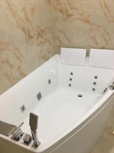 baño con bañera blanca y pared de mármol en 4-room jacuzzi apartment, en Leópolis