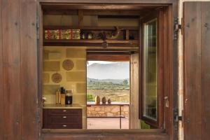 een keuken met een raam met uitzicht op een balkon bij The Carob Tree Cottage in Kambánion