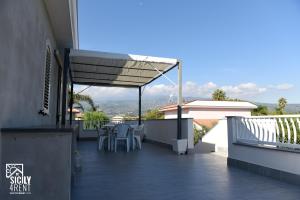 a patio with a table and chairs on a balcony at Sicily for Rent in Mascali